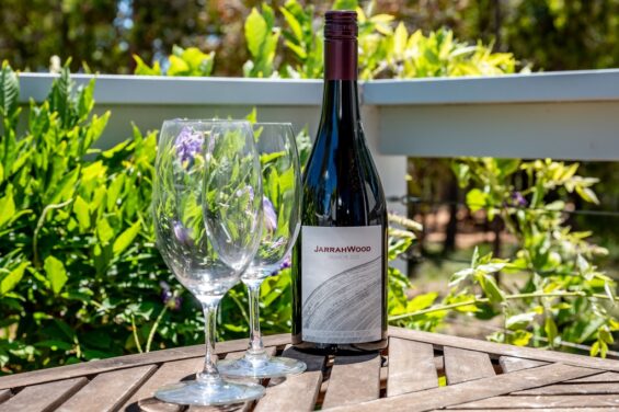 JarrahWood Grenache Bottle of red wine on an outdoor table with vines in the background