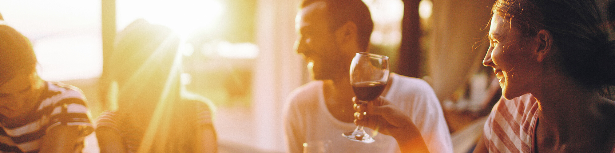 Happy smiling friends drinking wine at sunset at a Seashells resort acommodation