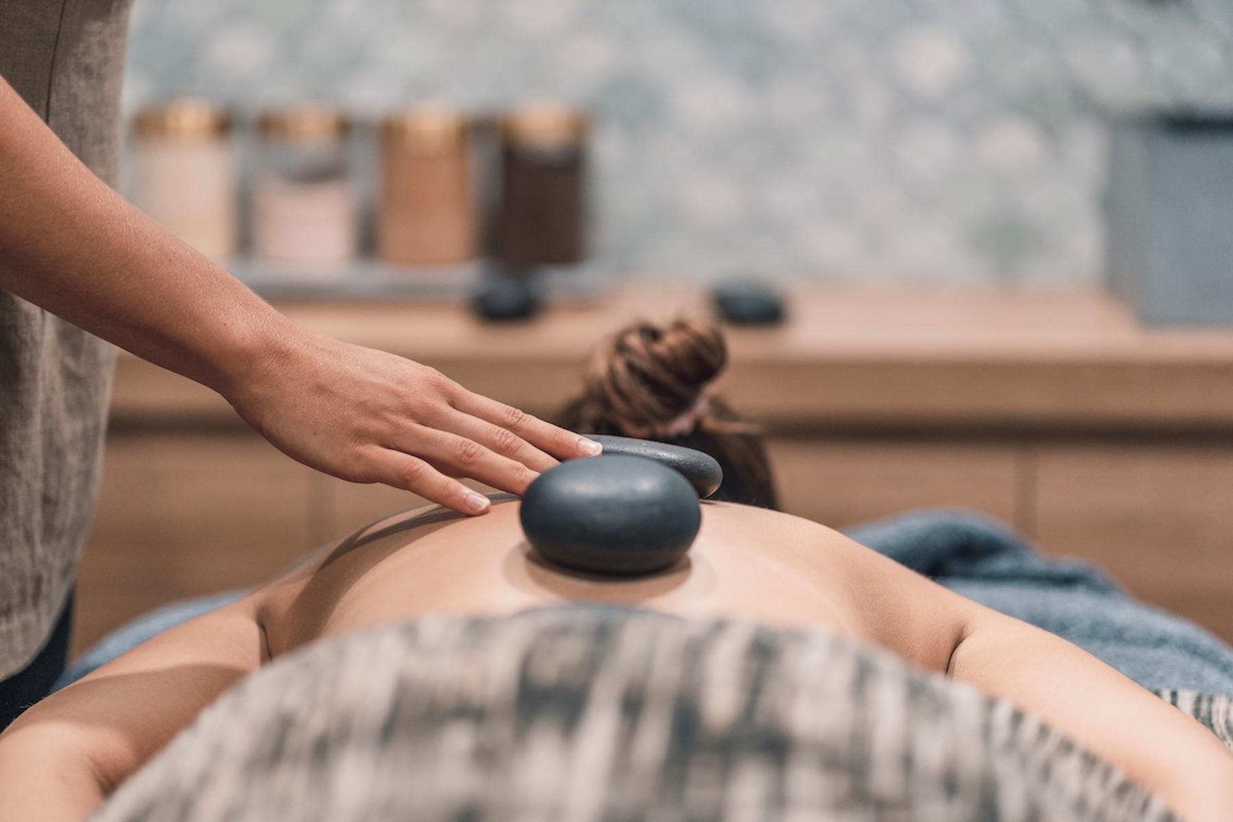 A lady lying on a massage table with stones on her back for a relaxation massage